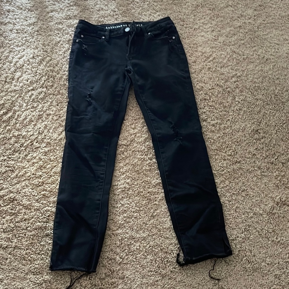 Black jeans with small rips and cut ends.